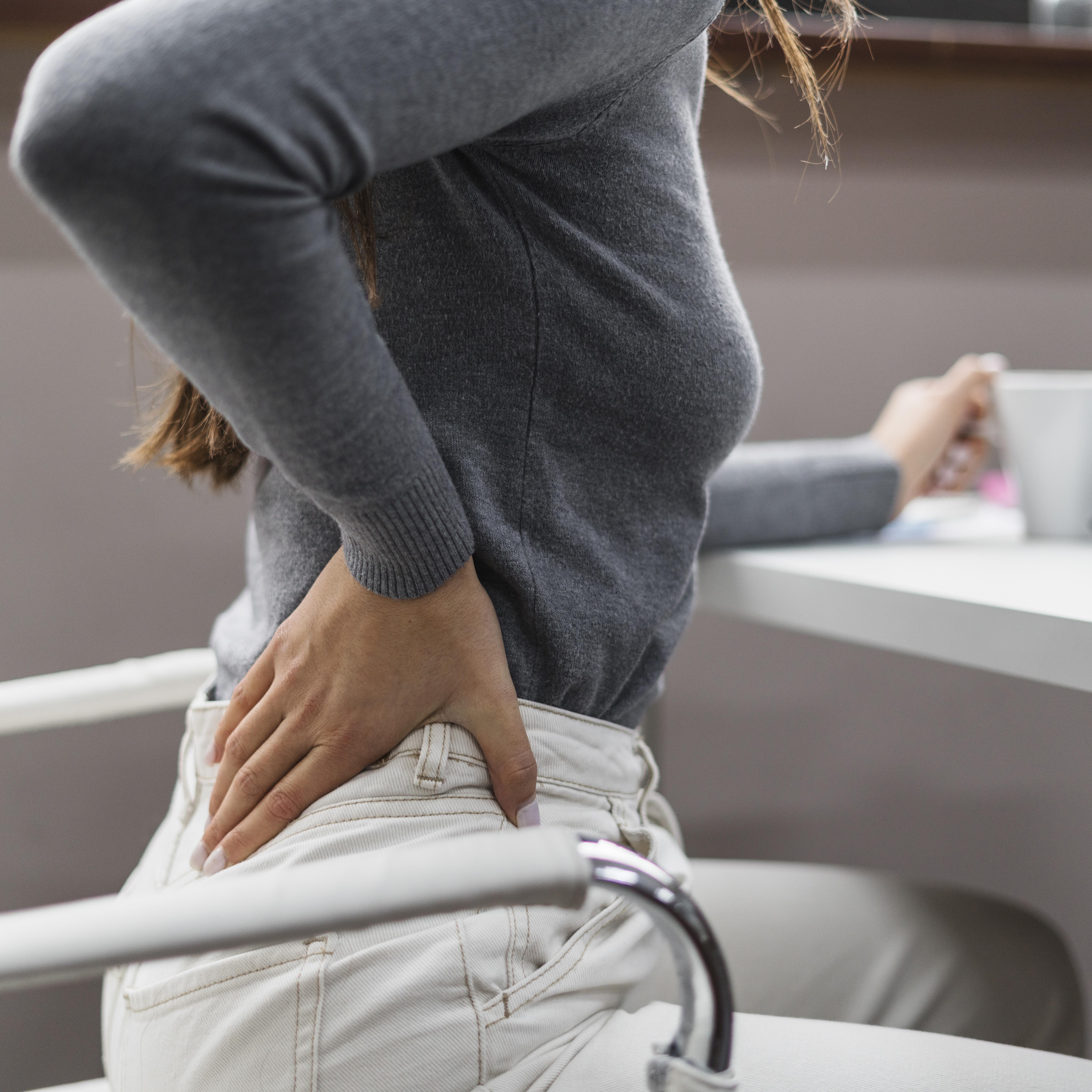 mujer-de-lado-con-dolor-de-espalda-mientras-trabaja-desde-casa